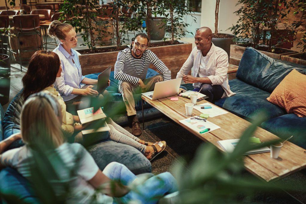 Diverse young businesspeople meeting around a coffee table at work